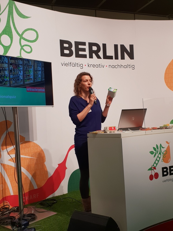 Eine Mitarbeiterin der Verbraucherzentrale Berlin auf der Bühne beim Regionalquiz