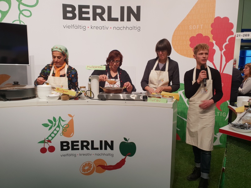 Kochaktion mit der Staatssekretärin Gottstein und türkischen Frauen auf der Bühne der Berlin-Halle