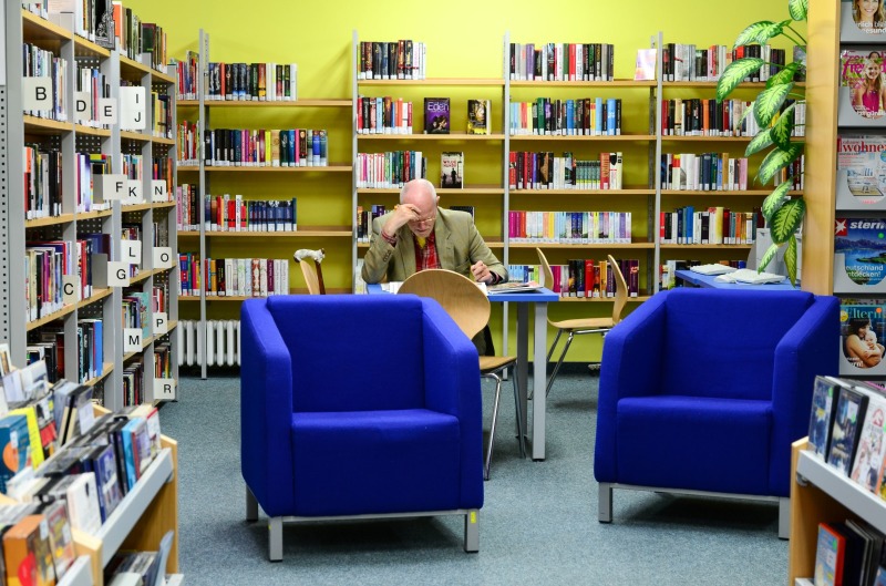 Blaue Sessel mit Zeitung lesendem Mann im Hintergrund