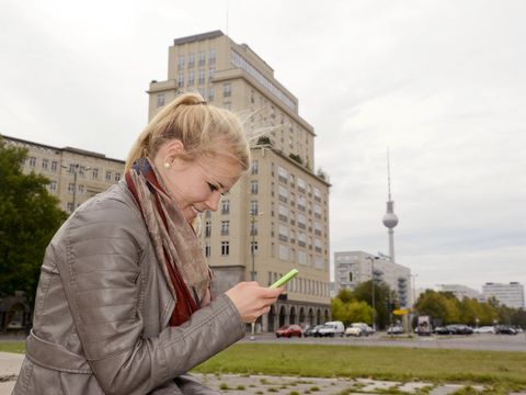 Junge Frau mit Smartphone am Strausberger Platz