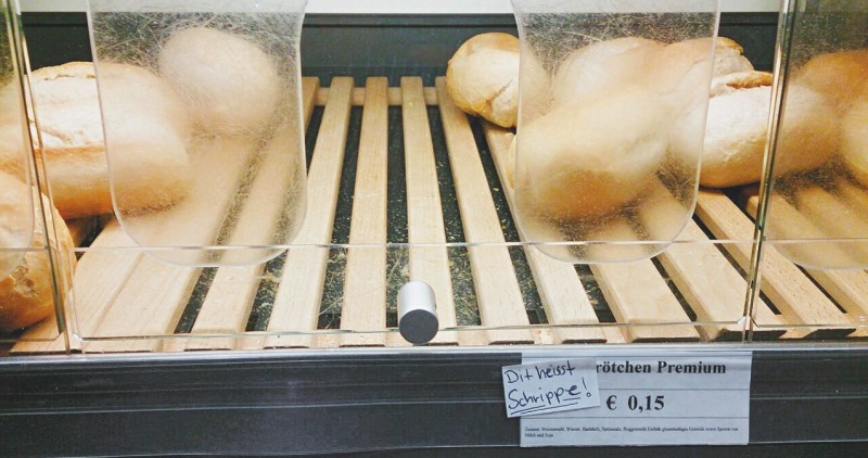 Backwarenauslage mit Brötchen und einem Zettel "Dit heisst Schrippe!"