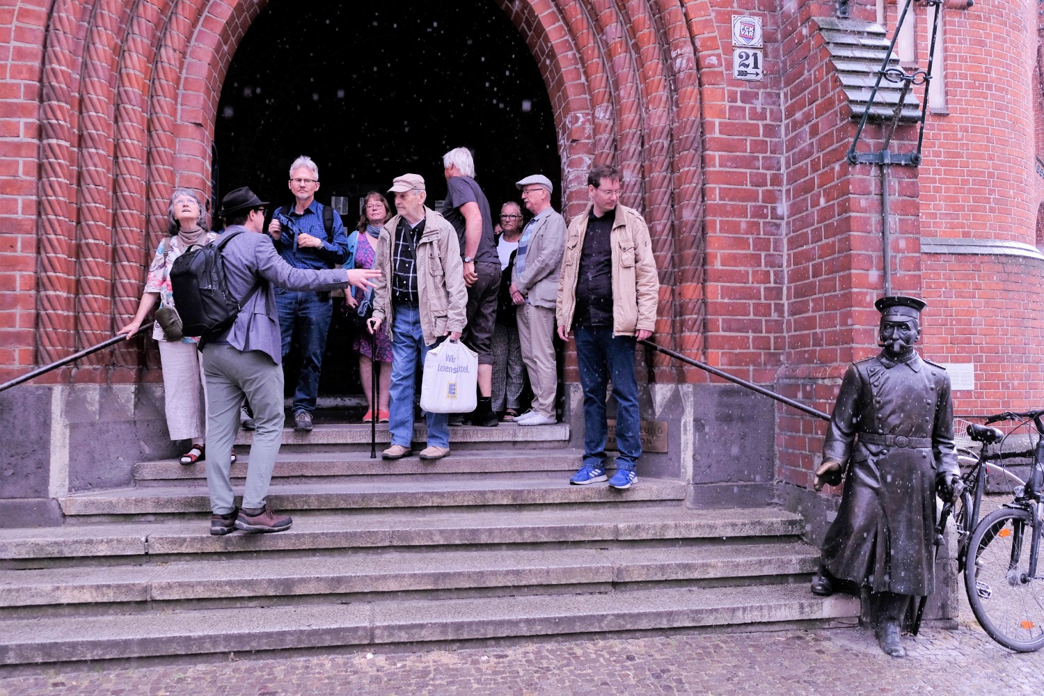 Die Spazierganggruppe am Eingang des Rathauses mit dem metallenen Hauptmann von Köpenick