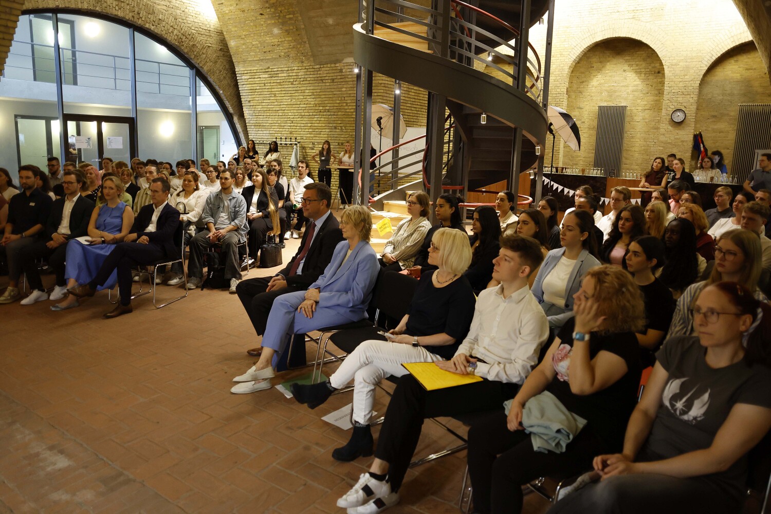 Alle Teilnehmenden (w/m/d) der Ernennungsveranstaltung sitzend im Turmfoyer.