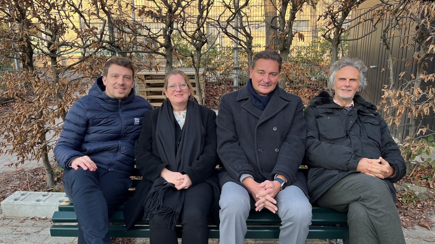 Daniel-Jan Girl, Vorstand von Global Goals für Berlin e.V., Bezirksstadträtin Heike Schmitt-Schmelz, Schulleiter Sven Zimmerschied und Bezirksstadtrat Oliver Schruoffeneger auf der "Global Goals"-Bank an der Friedensburg-Oberschule