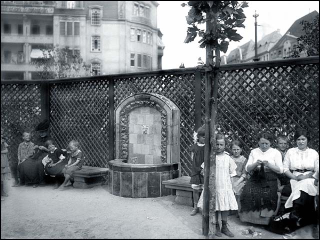 Historisches Foto von Erwin Barth - Gustav-Adolf-Platz (Mierendorffplatz), Majolika-Trinkbrunnen und Holzspalier auf dem Spielplatz, um 1913