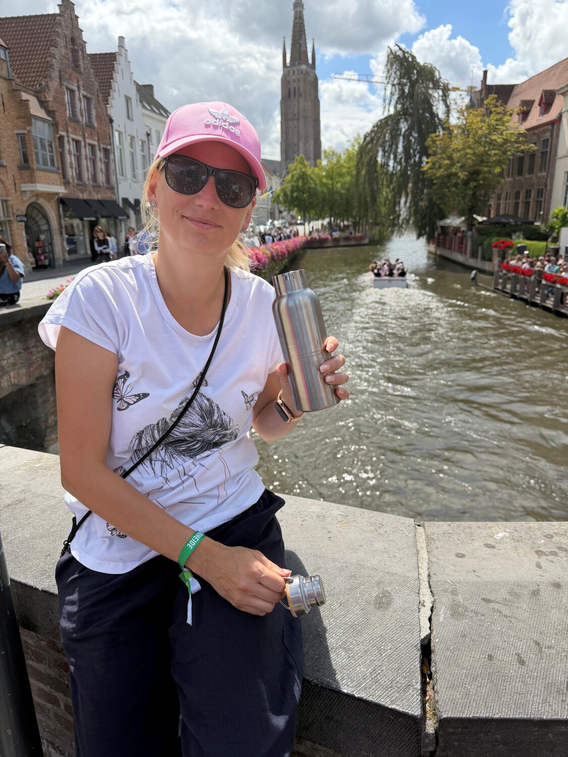 Person lehnt sich an die Brüstung einer steinernen Brücke und hält eine Edelstahlflasche in der Hand