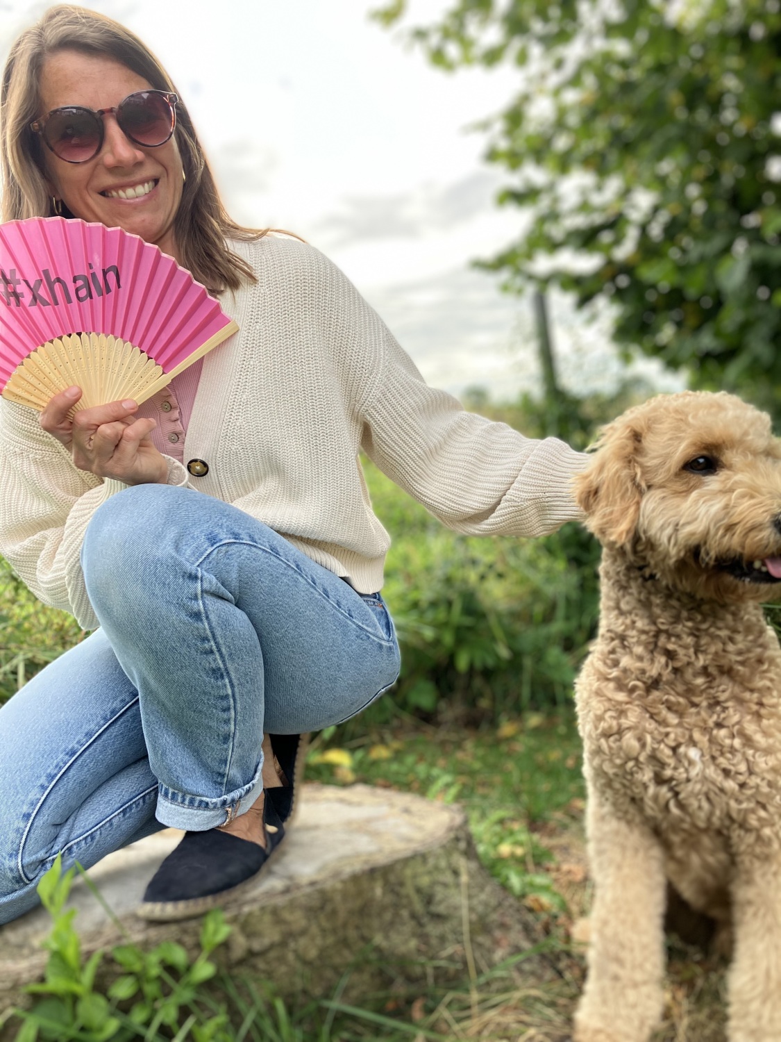 Person mit Hund und einem pinken Fächer in der Hand