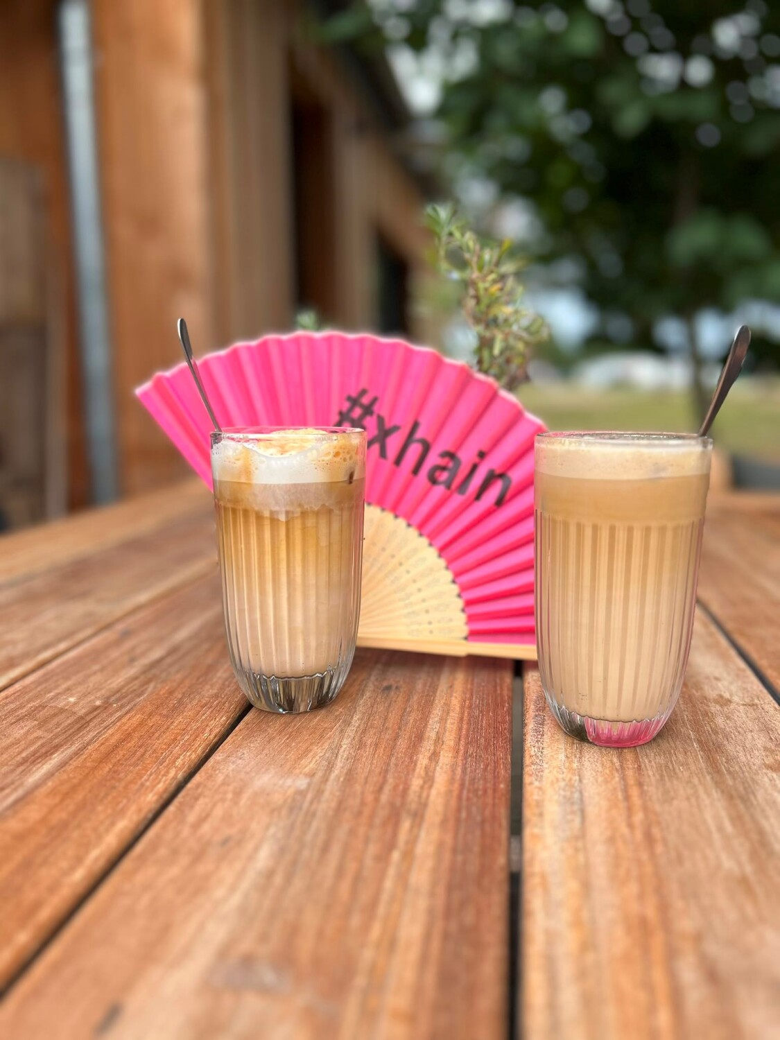 Pinker Fächer hinter zwei Latte Macchiato-Gläsern