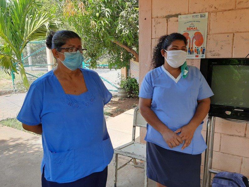 Zwei Frauen mit Maske vor einem Gesundheitszentrum 