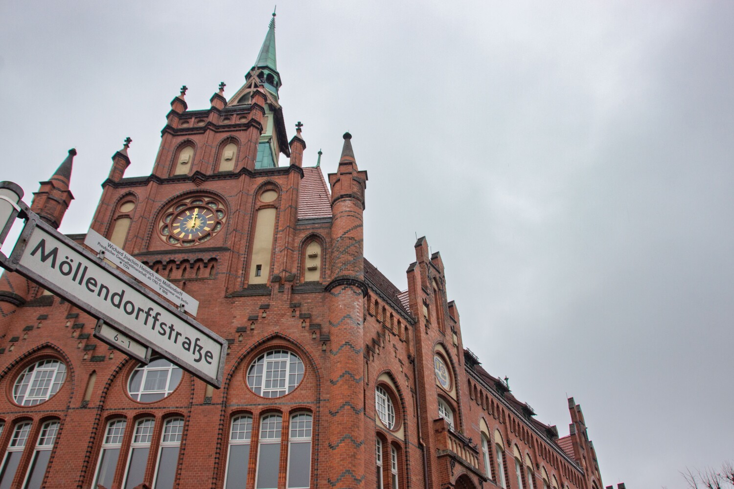 Im Vordergrund ist das Straßenschild "Möllendorffstraße zu sehen, im Hintergrund das entrüstete und sanierte Rathaus Lichtenberg.