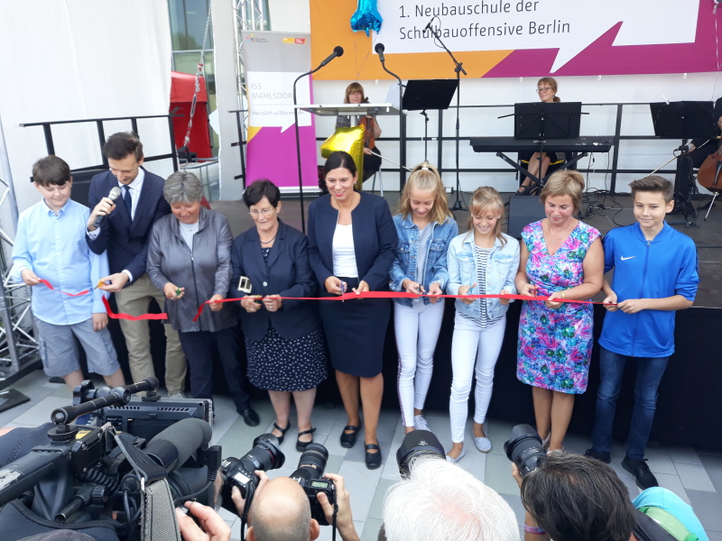 Das Durchschneiden des roten Bandes mit vereinten Kräften: Gordon Lemm, Senatorin Katrin Lompscher, Bezirksbürgermeisterin Dagmar Pohle, Senatorin Sandra Scheeres, Sibylle Fricke und Schülerinnen und Schüler.
