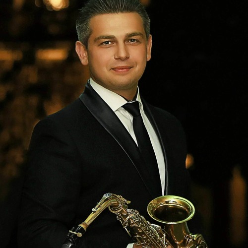 Das zweite Farbfoto ist ein Porträt vom Musiker Wlad Ginzburg mit einem Saxophon.