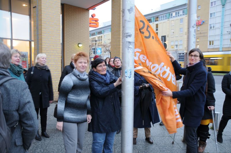 Petra Pau, Dagmar Pohle und Maja Loeffler hissen die Fahne "Gewaltfrei leben - Nein zu Gewalt an Frauen"