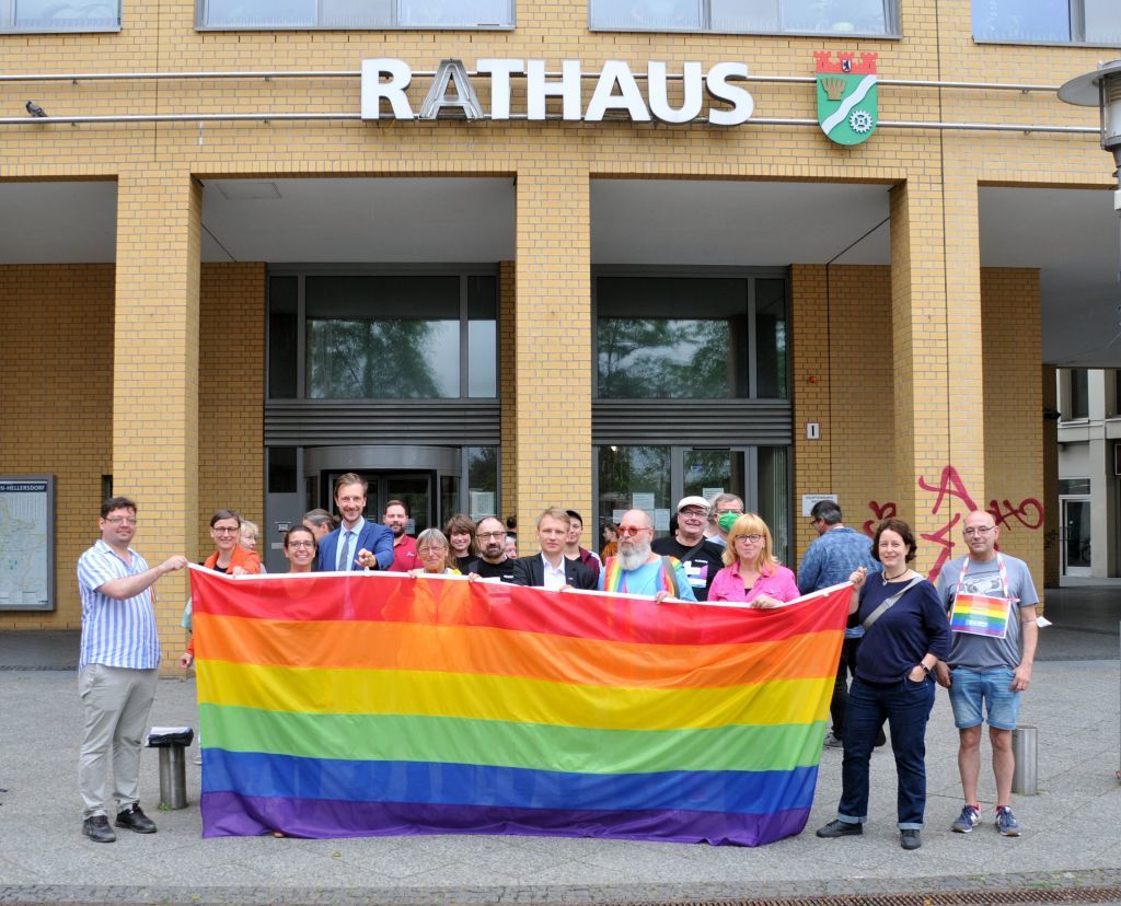 Hissen der Regenbogenfahne vor dem Rathaus 2021 - Die Teilnehmenden präsentieren die Fahne