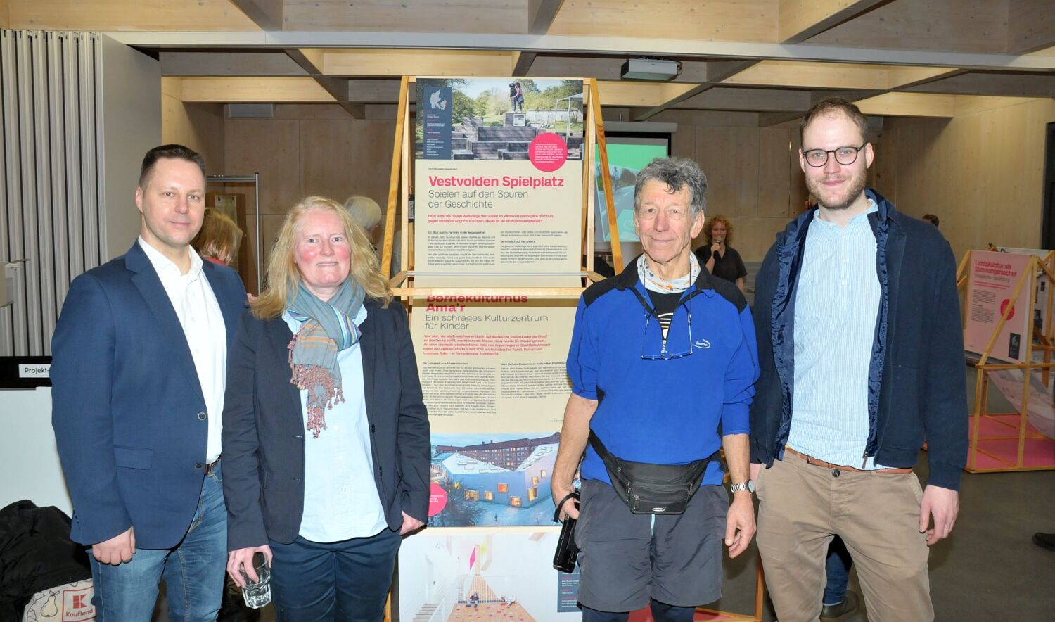 Ausstellung „Lebenswerte Stadt - 28 x Stadtentwicklung in Dänemark" - Bezirksstadtrat Stefan Bley, Birgitte Tovborg-Jensen, Radfahrer des ADFC und Paul Robin Greiner vor einem Plakt der Ausstellung