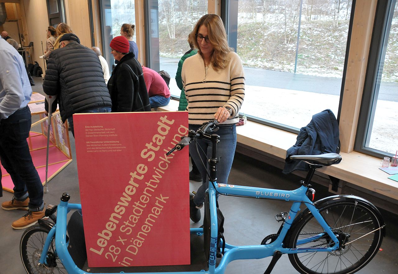 Ausstellung „Lebenswerte Stadt - 28 x Stadtentwicklung in Dänemark" - Lastenfahrrad mit Besucherin