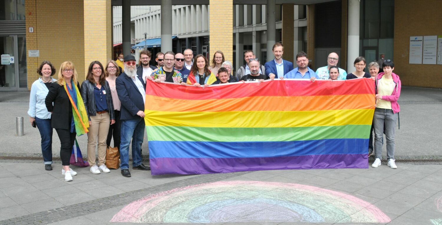 IDAHOBIT 2022 - Gruppenbild mit Regenbogenflagge, Bezirksbürgermeister, Bezirksstadträtinnen und Aktivistinnen und Aktivisten vor dem Rathaus