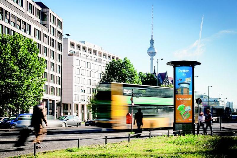 Plakate der Marzahn-Hellerdorf Serie in einer beleuchteten Litfaßsäulen mit dem Fernsehturm im Hintergrund