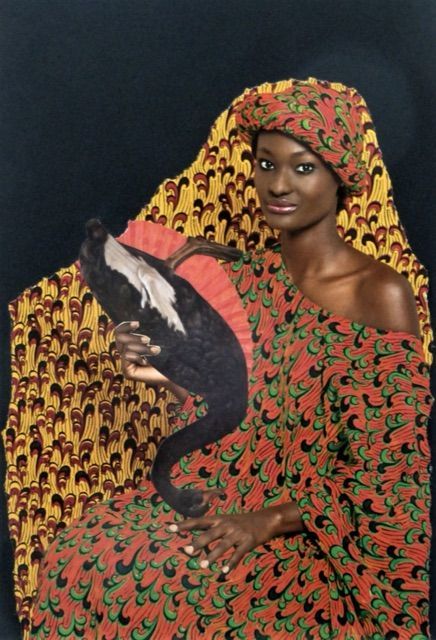 Auf dem Bild sitzt eine schwarze Frau in einem gelb-roten Gewand vor schwarzem Hintergrund. Sie hält einen schwarzen Schwan kopfüber in den Händen. Es ist eine Papiercollage.