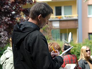 Mann vor Hochhaus im begrünten Innenhof