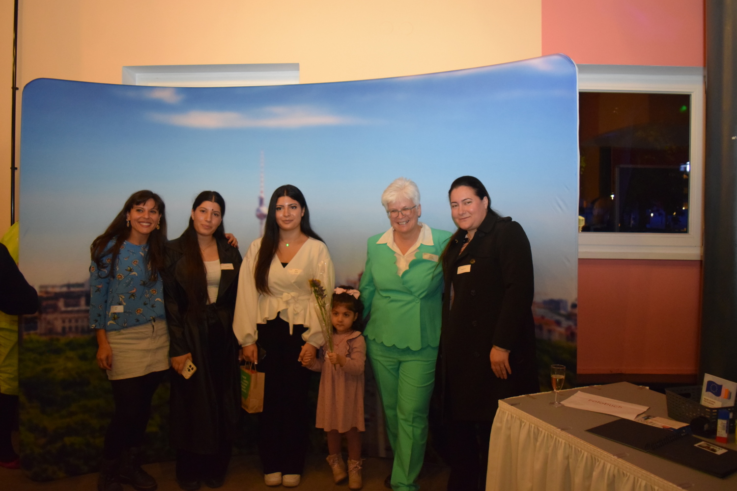 Teilnehmende der Einbürgerungsfeier in Berlin-Mitte und Bezirksbürgermeisterin Stefanie Remlinger vor einer Fotowand.