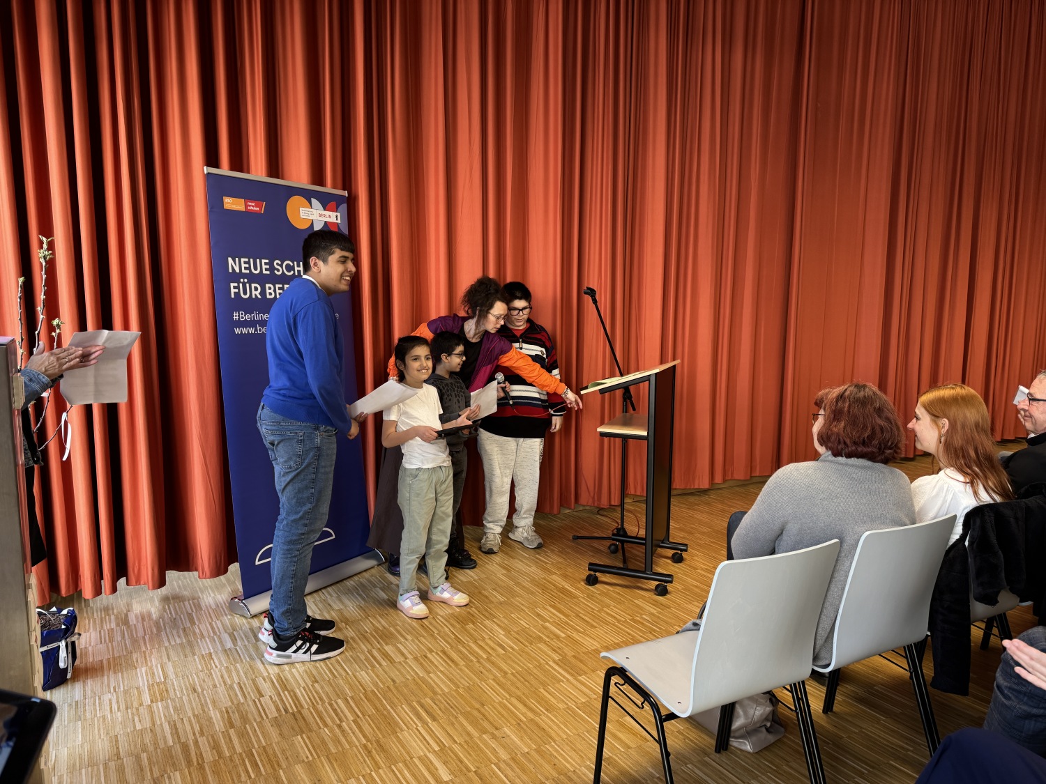 Schüler*innen erzählen auf der Bühne der Eröffnungsfeier, was ihnen besonders gut am Neubau gefällt