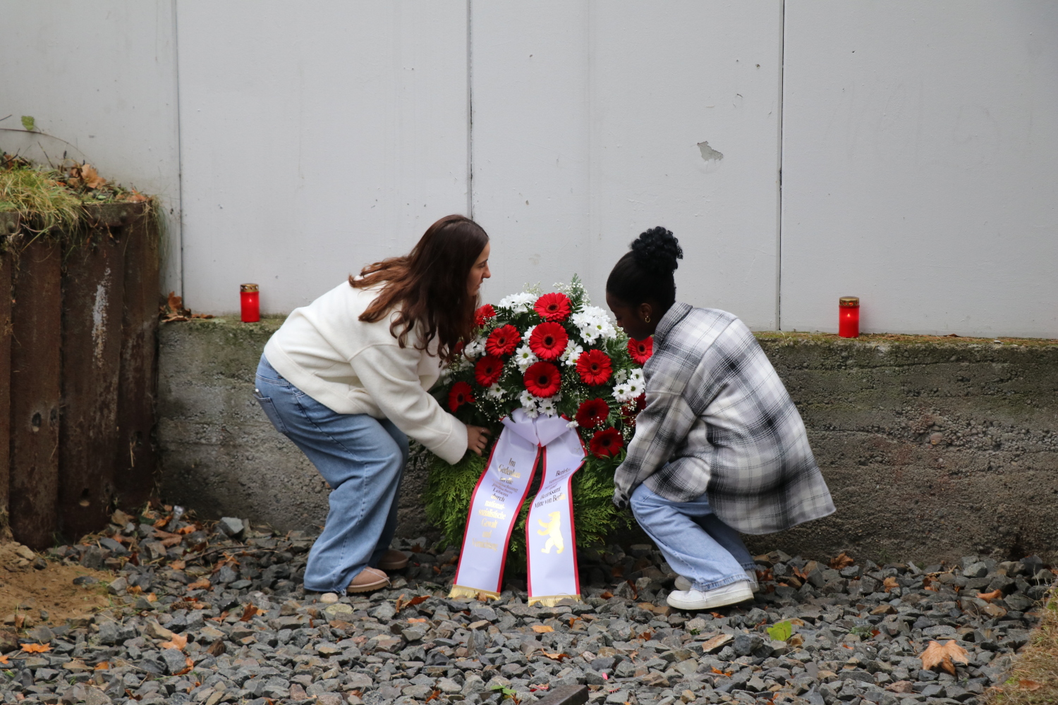 Zwei Schüler*innen legen einen Kranz am Gleis des Güterbahnhofs nieder.