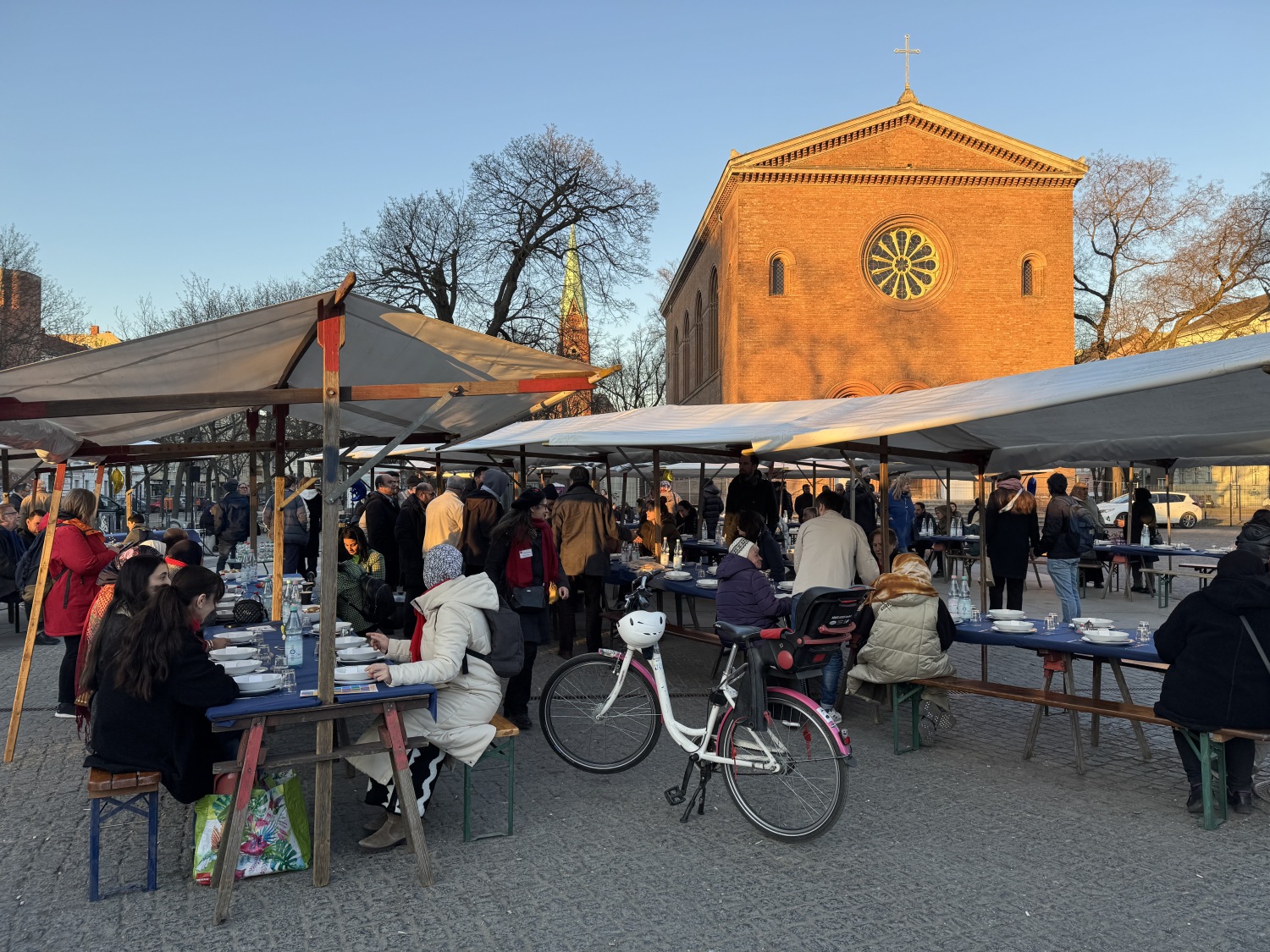 Menschen sitzen beim gemeinsamen Fastenbrechen auf Bänken am Leopoldplatz zusammen.