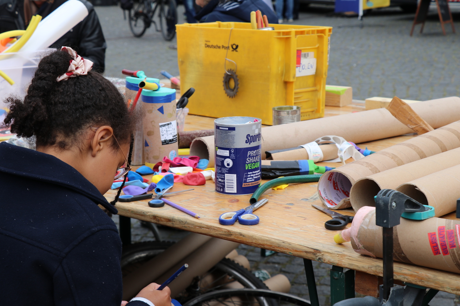 Kind bastelt ein Instrument aus Papierrollen und alten Schläuchen