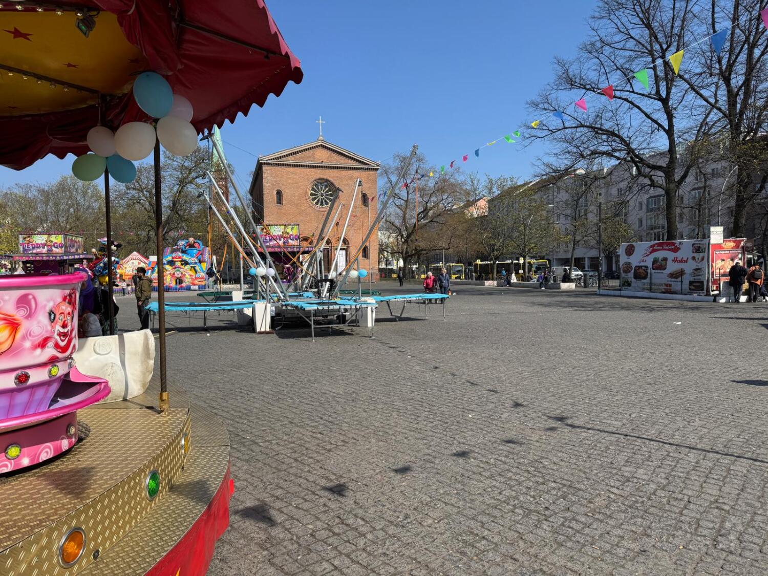 Zu sehen ist ein Karussell auf dem Leopoldplatz. Im Hintergrund ist die Nazarethkirche zu sehen.