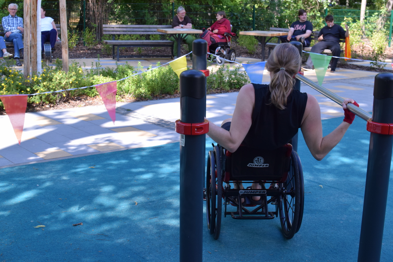 Eine Rollstuhlfahrerin trainiert an einem Barren auf dem Spielplatz an der Mollstraße 8-11.