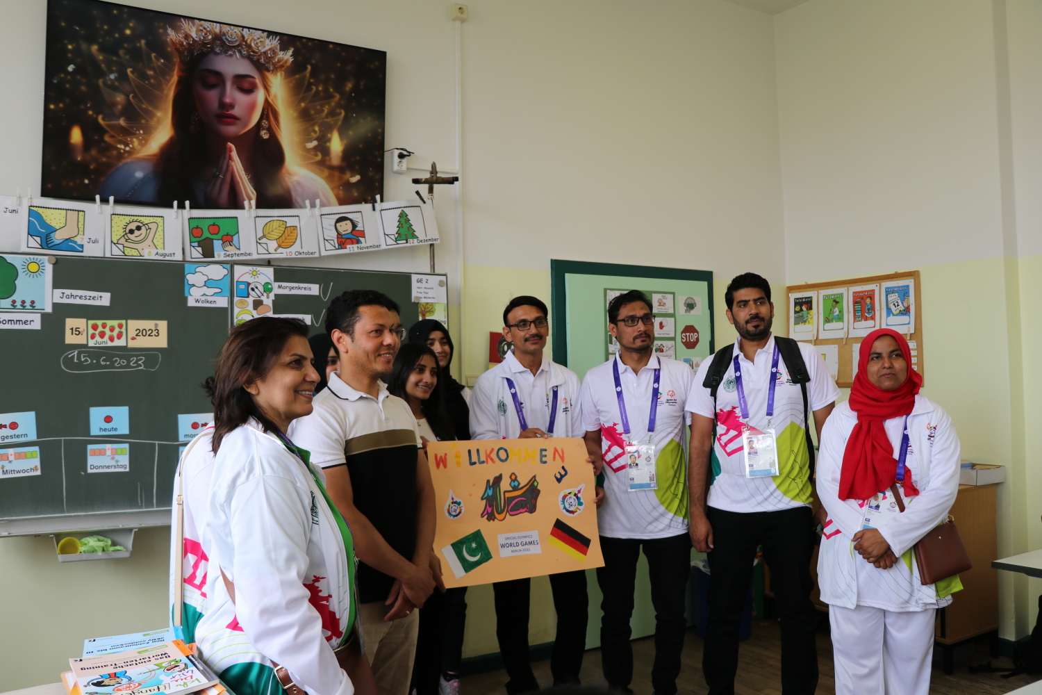 Pakistanische Athlet*innen in einem Klassenraum mit einem Begrüßungsplakat der deutschen Schüler*innen