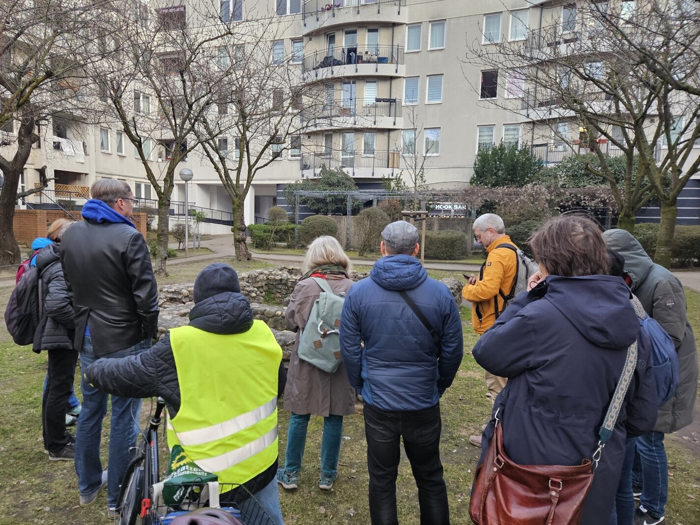Menschen stehen vor einer niedrigen Steinmauer