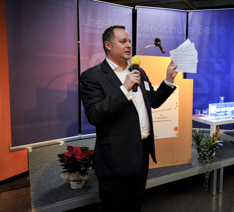 Falko Liecke mit Mikrofon und Moderationskarten in der Hand
