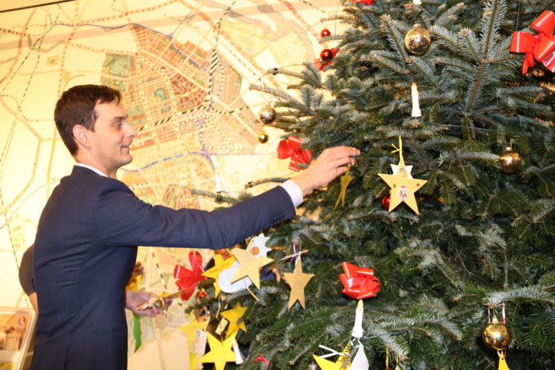 Bezirksbürgermeister Hikel schmückt den Wunschbaum im Foyer des Rathause mit den Wunschsternen der Kinder.