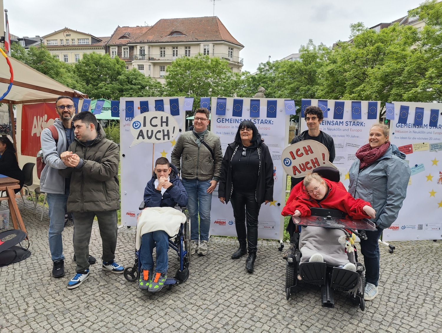 Die Besuchenden aus der Förderstätte haben sich mit Katharina Smaldino vor den gesammelten Forderungen positioniert und halten zwei Schilder mit der Aufschrift: Ich Auch!