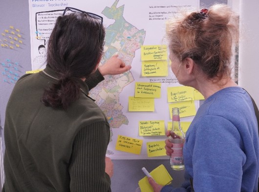 Zwei Teilnehmende markieren belastete Orte an einer Karte.