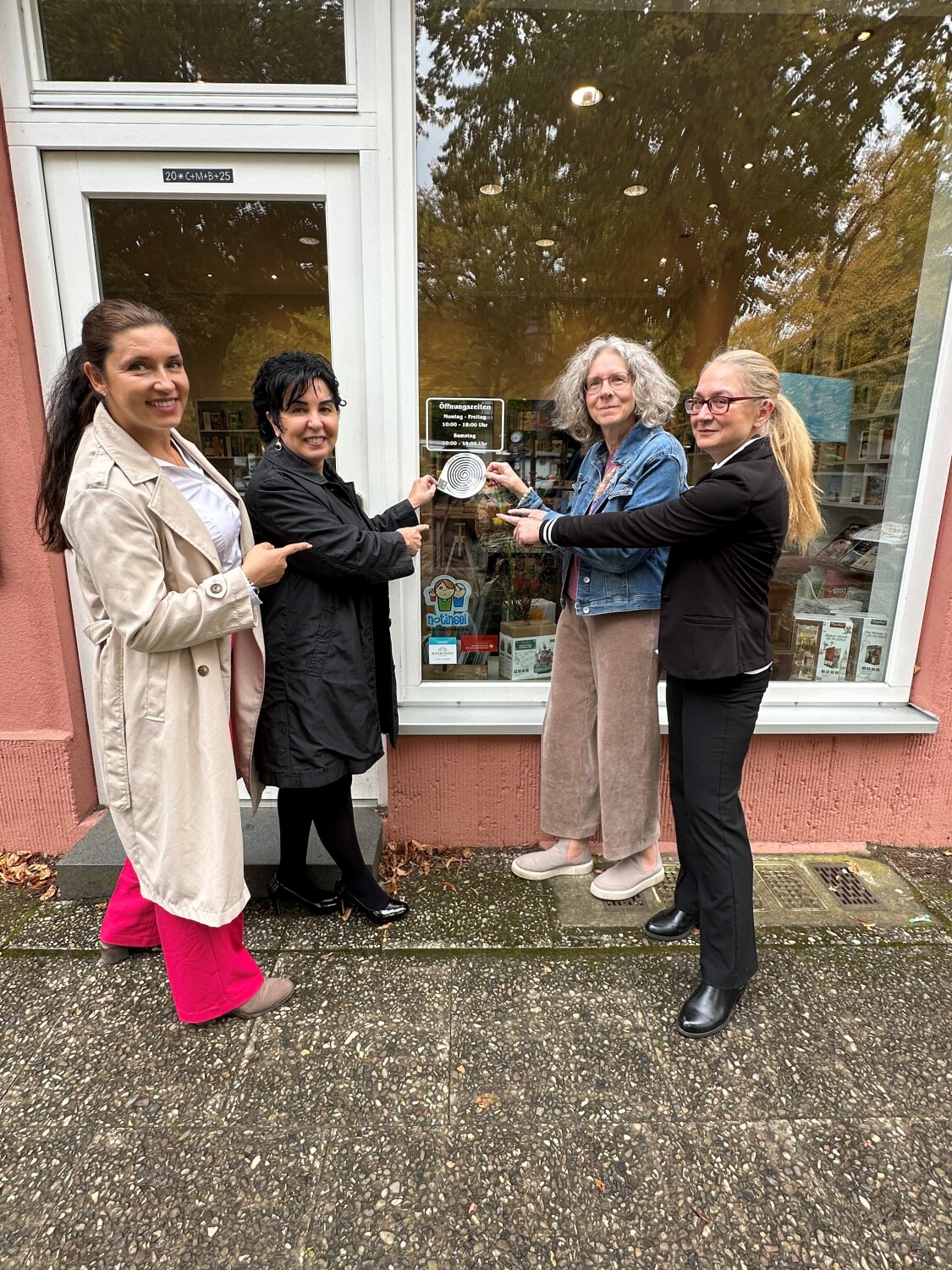 v.l.: Einsamkeits- und Ehrenamtsbeauftragte Katharina Schulz, Bezirksbürgermeisterin Emine Demirbüken-Wegner, Heike Kornfeld und Rivkah Netzer (Geschäftsführerinnen der Buchhandlung am Fellbacher Platz) beim Anbringen des Stickers gegen Einsamkeit an der Buchhandlung
