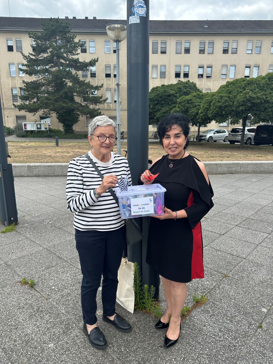 Bezirksbürgermeisterin Emine Demirbüken-Wegner nimmt Friedenskraniche von Elke Rusteberg entgegen.