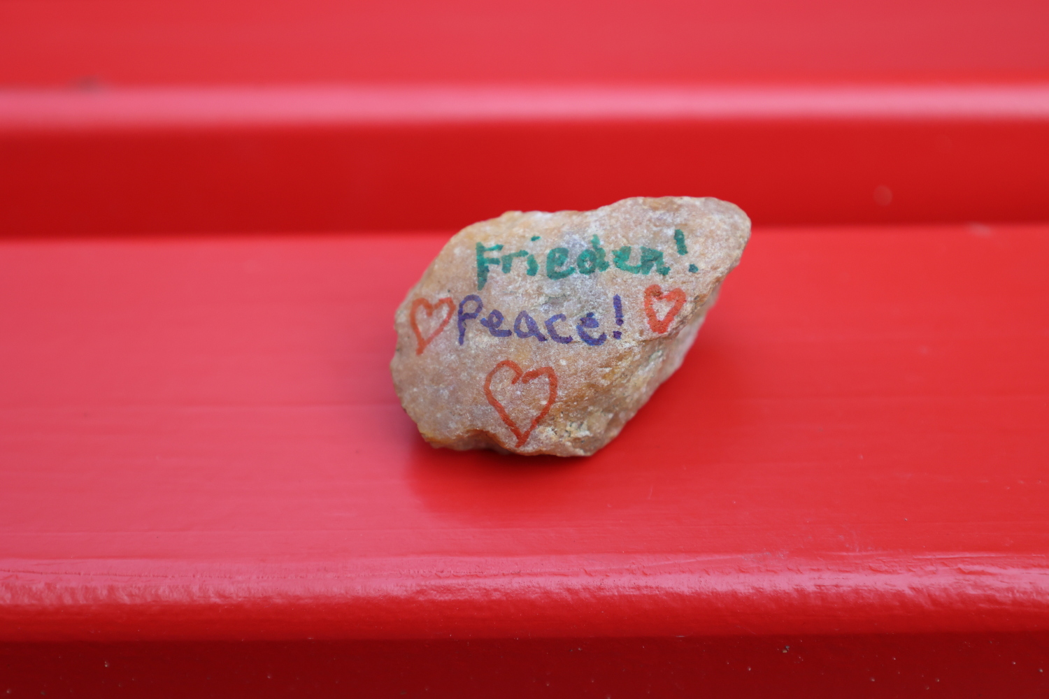 Bemalter Stein mit Herzen und dem Schriftzug Frieden, Peace.