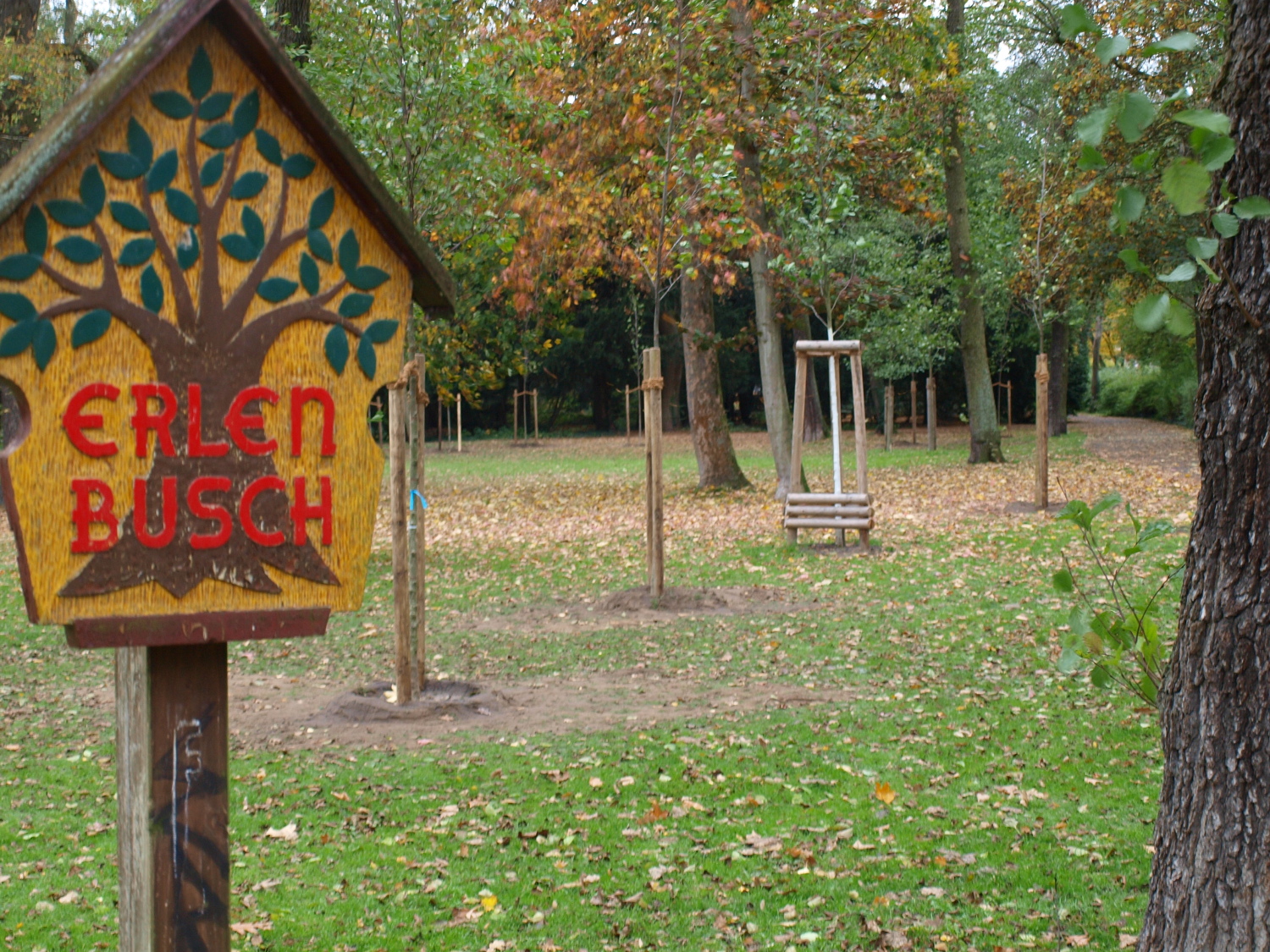 Das Erlenbusch-Schild mit Blick auf die neu gepflanzten Bäume