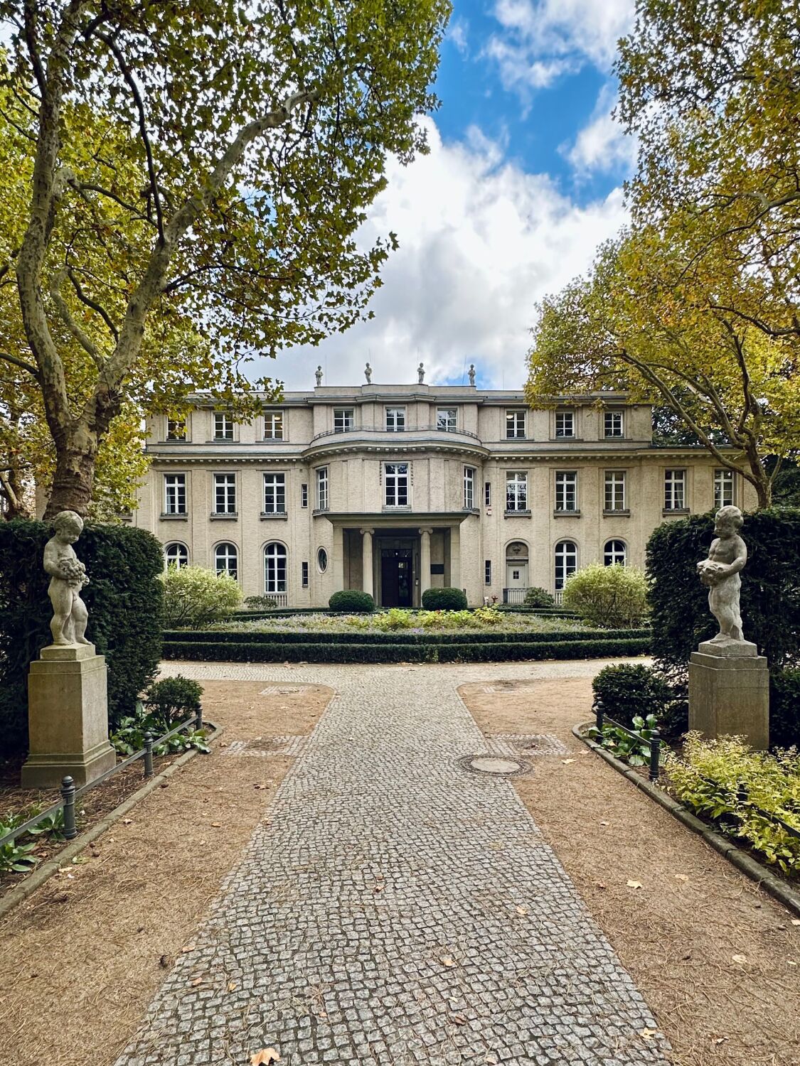 Blick auf die Zufahrt zum Gebäude mit kindlichen Figuren links und rechts