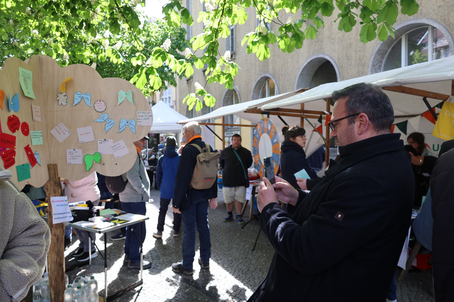 Bezirksstadtrat Aykal steht im Getümmel und fotografiert unseren Inklusionsbaum.