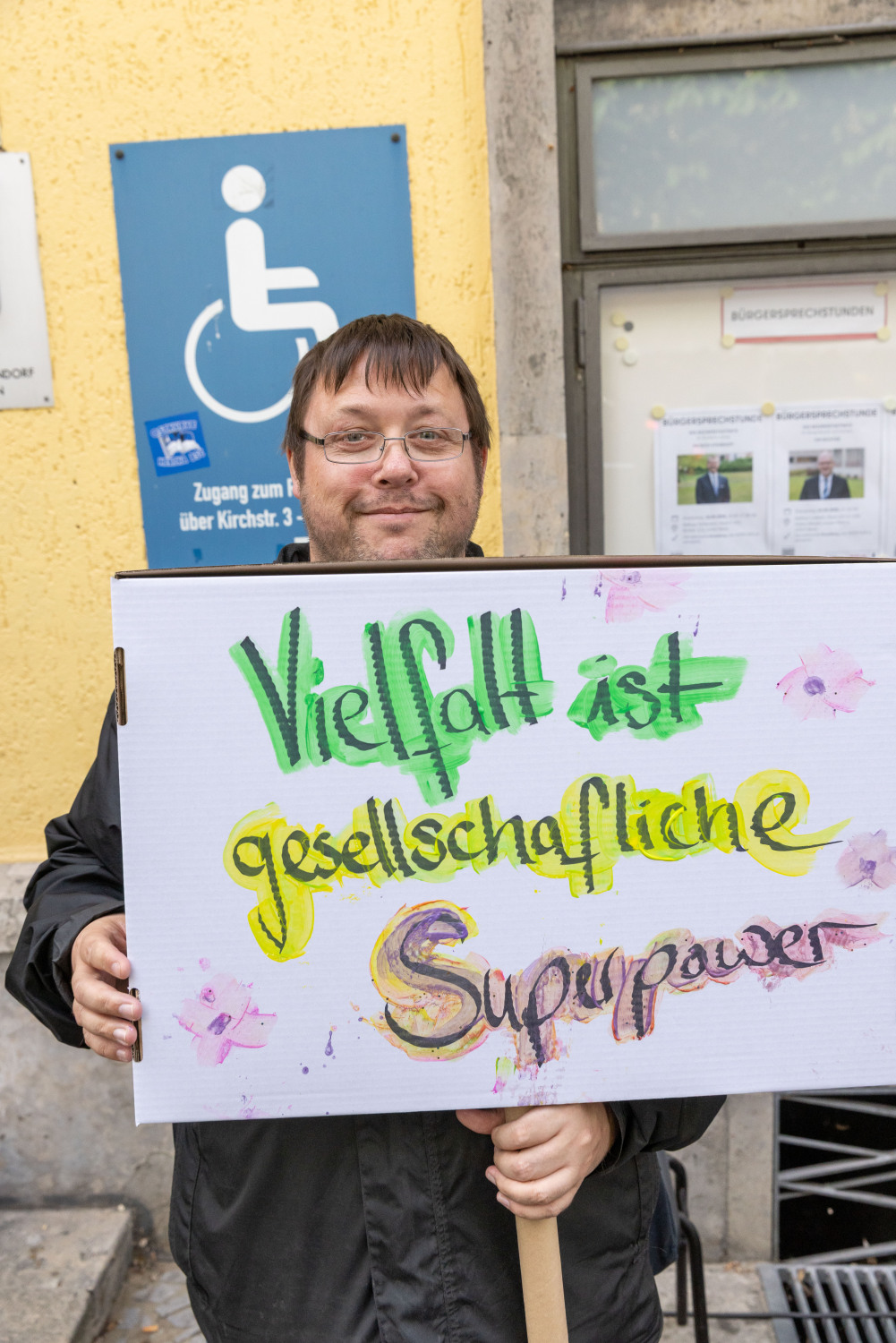 Ein Teilnehmer der Menschenrechtskette hält ein Demoschild auf dem in bunter Schrift steht "Vielfalt ist gesellschaftliche Superpower".