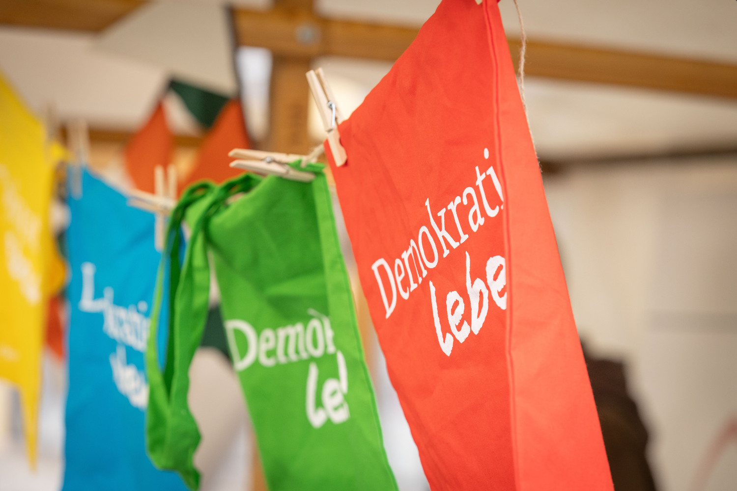 Stoffgirlande in gelb, blau, grün, rot mit weißer Schrift "Demokratie leben".