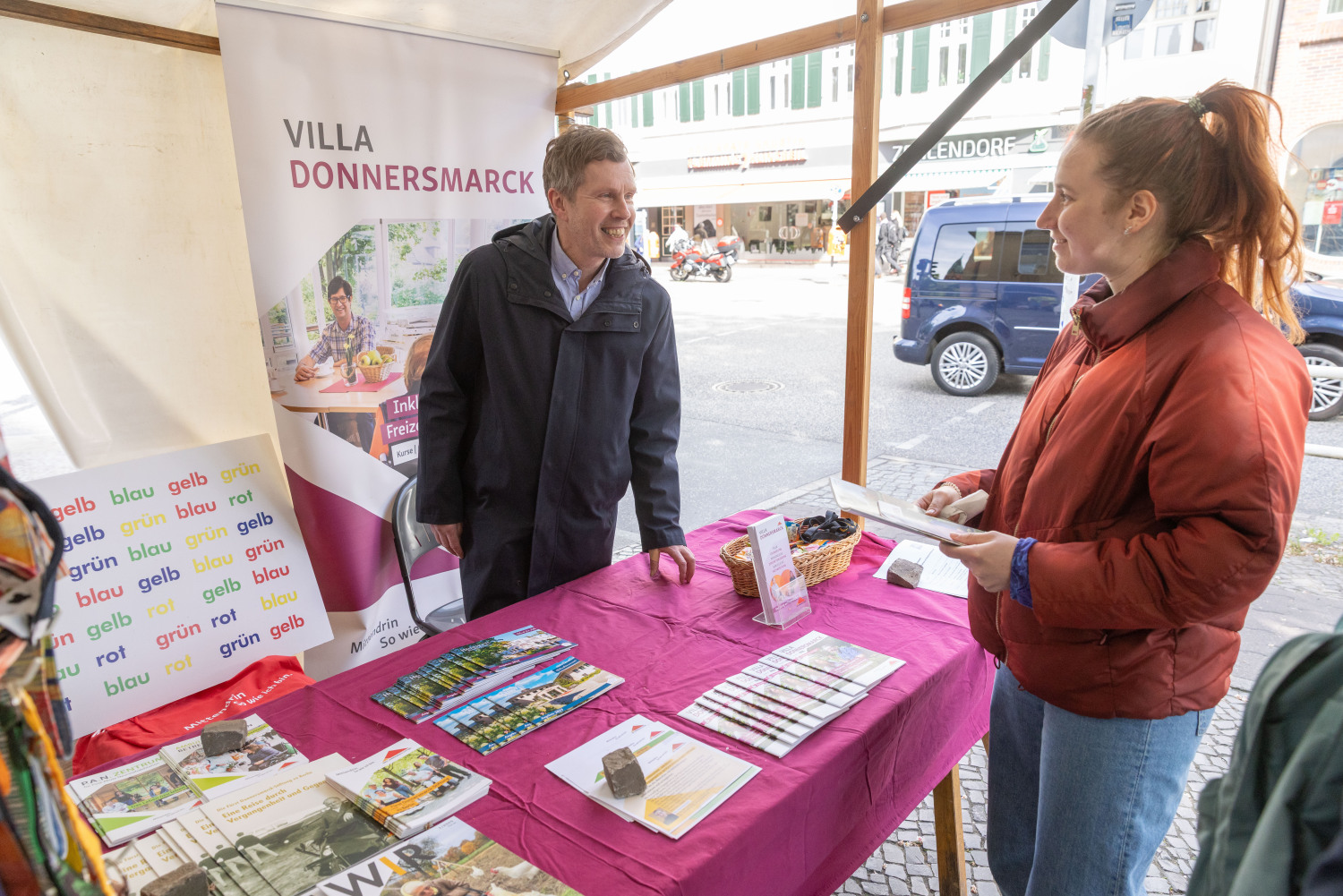 Eine Person informiert sich am Infostand der Villa Donnersmarck. Materialien sind gut sortiert ausgelegt.