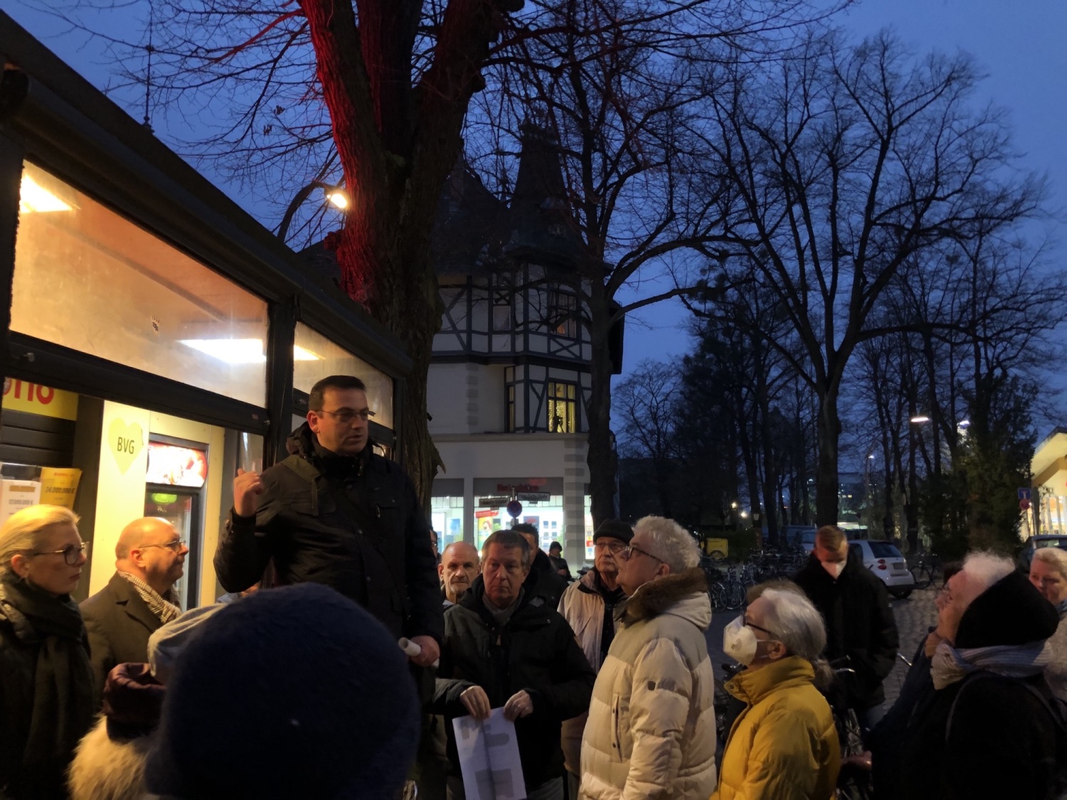 Bezirksstadtrat Aykal mit Teilnehmenden der Beteiligungswerkstatt vor dem Kiosk am Bahnhofsvorplatz