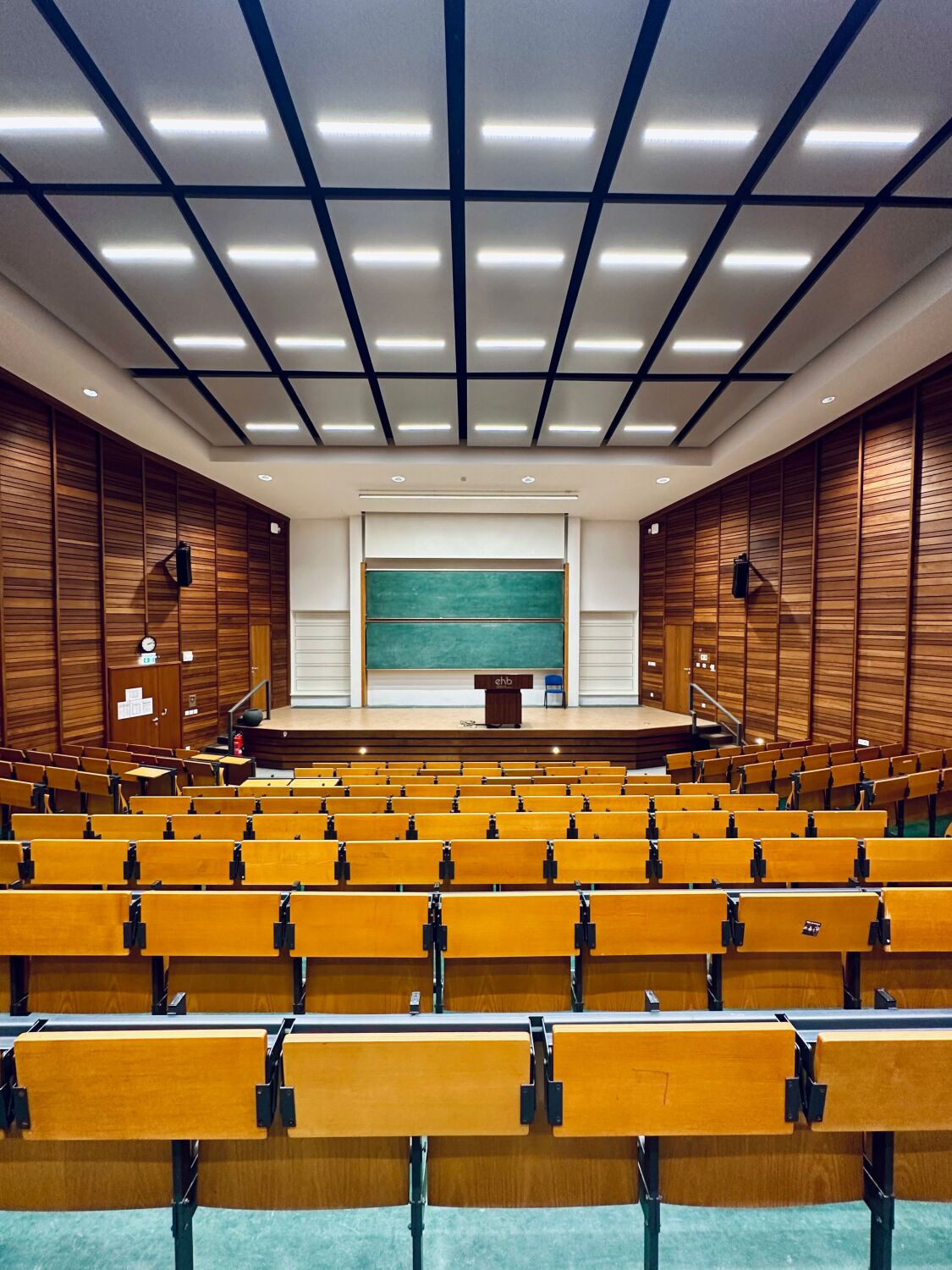 Zentraler Blick aus Richtung der Sitzbänken nach vorne zur Tafel des Audimax