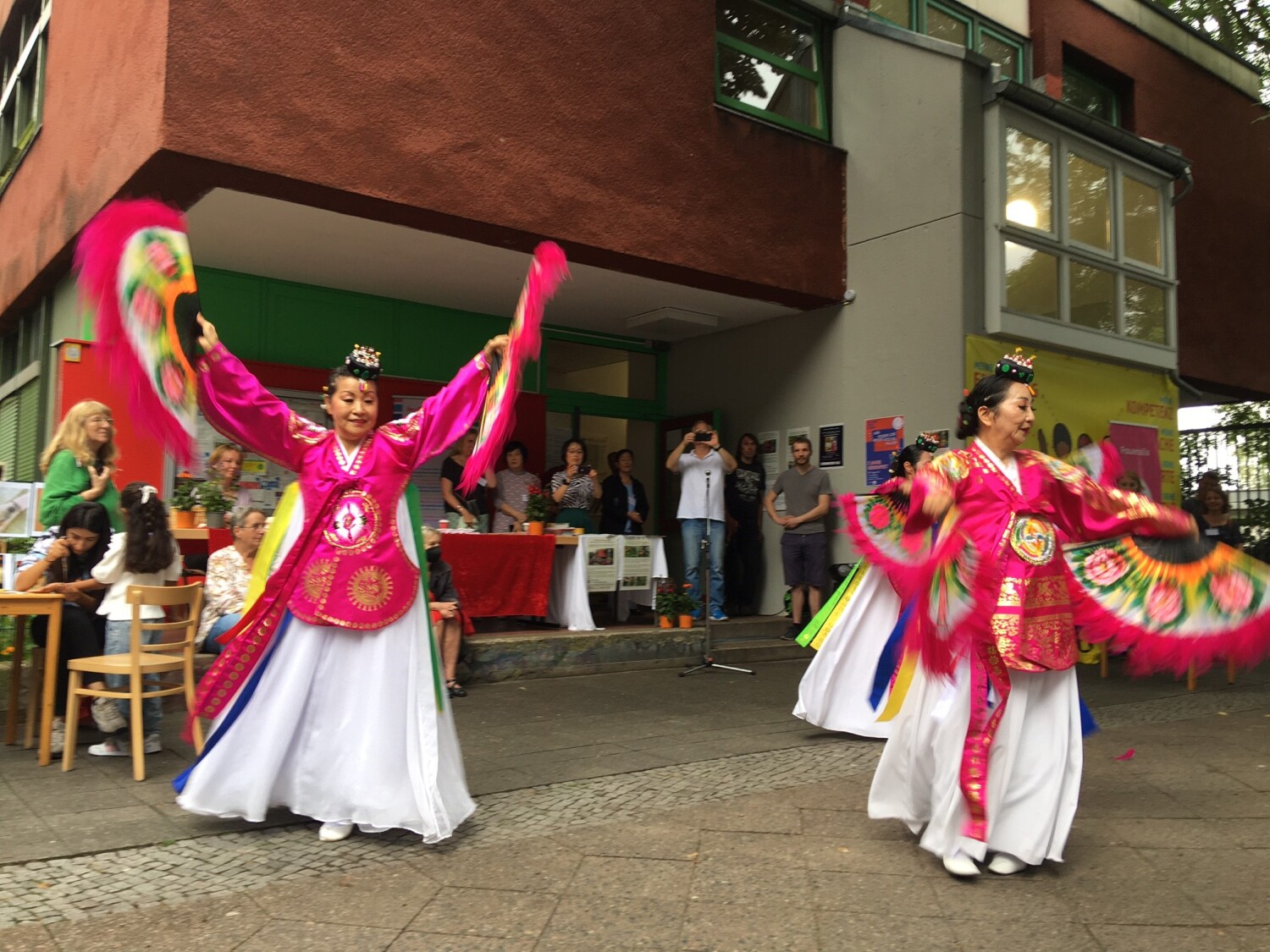 Drei Frauen in traditionell koreanischer Kleidung führen einen Tanz mit Fächern auf.