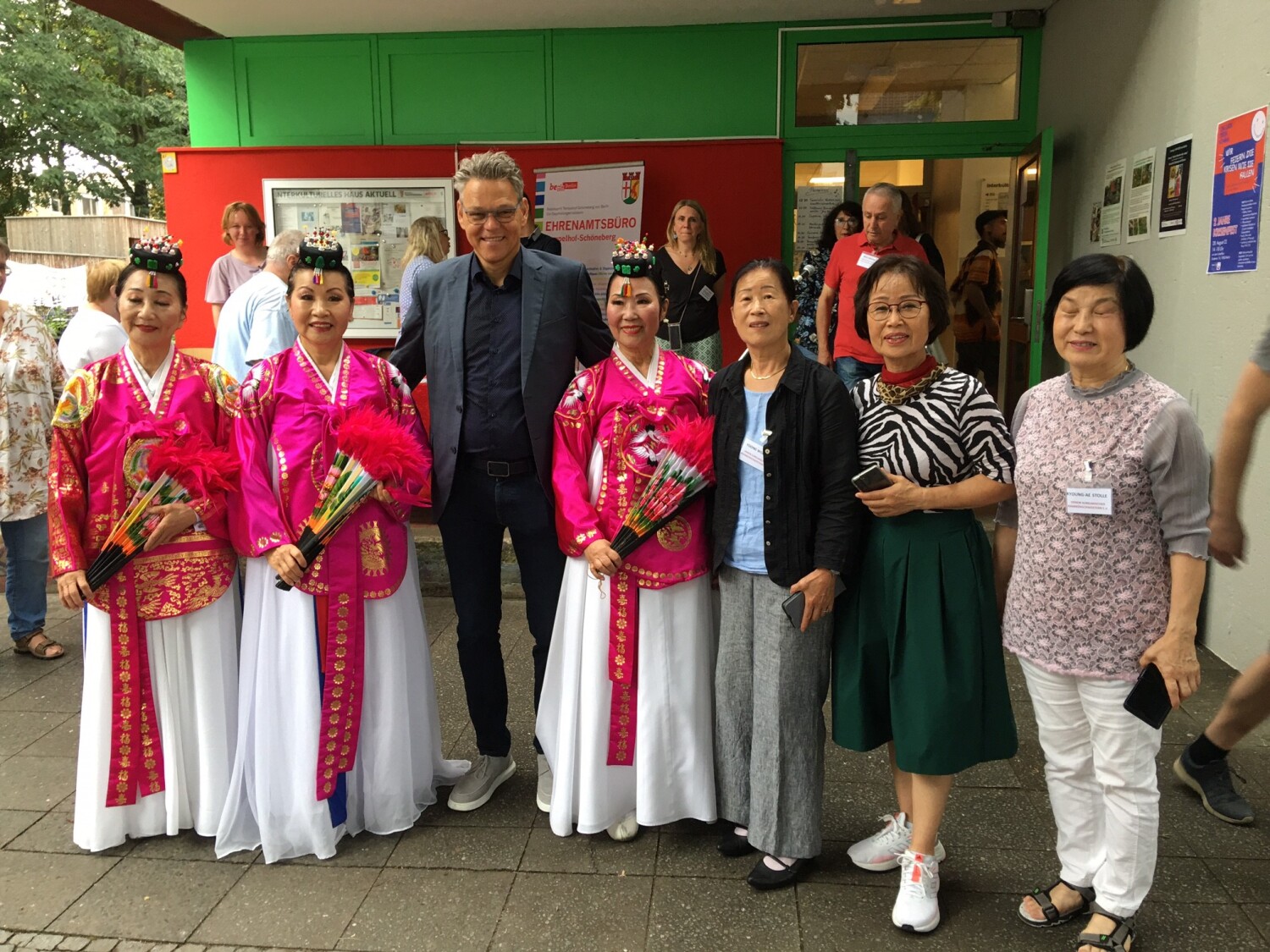 Ein Mann steht zusammen mit sechs Frauen, alle lächeln in die Kamera. Drei Frauen tragen traditionell koreanische Kleidung.